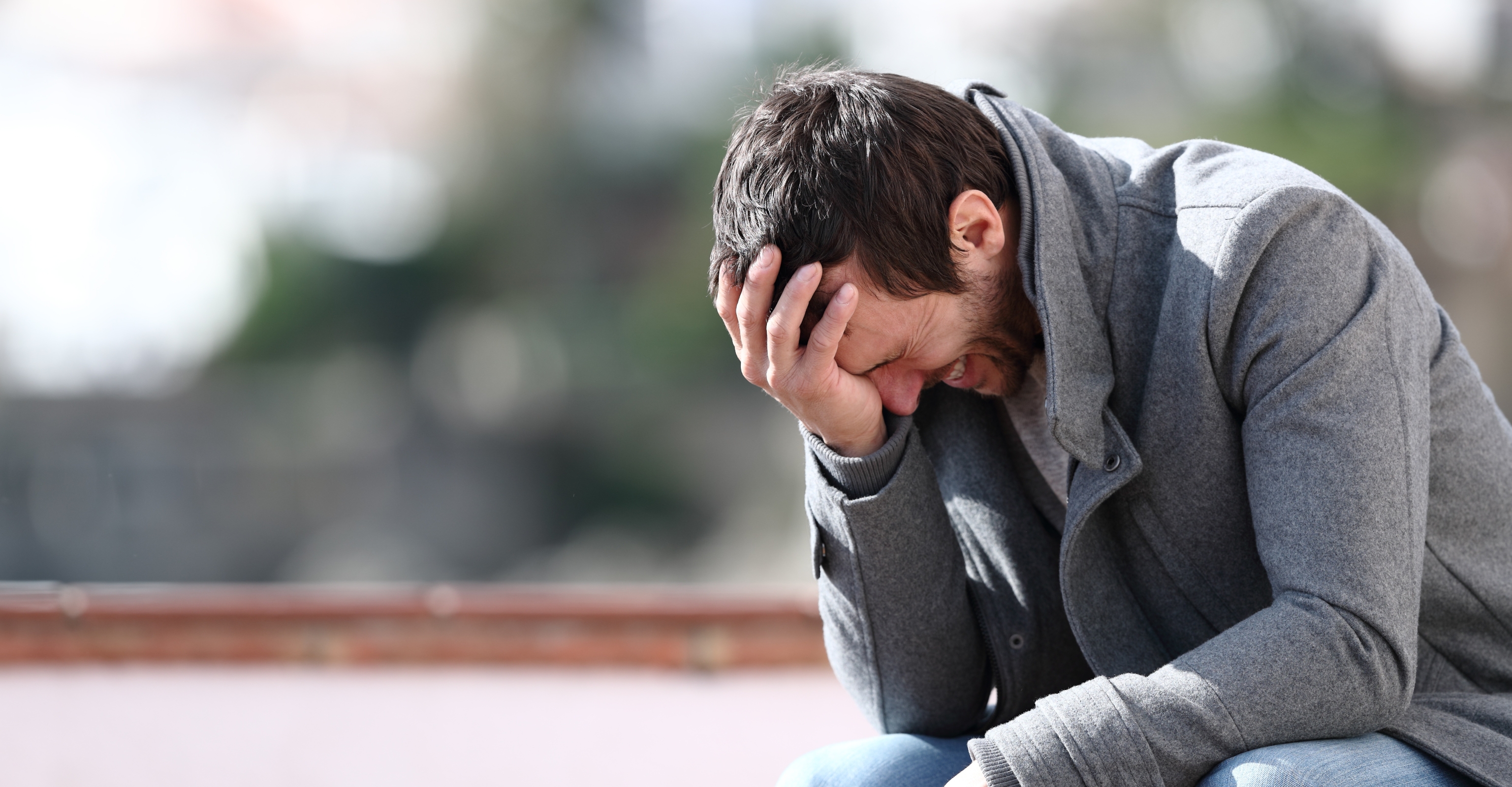Man sitting on park bench looking regretful