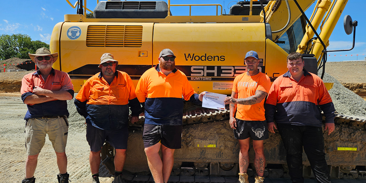 Men standing next to heavy machinery 