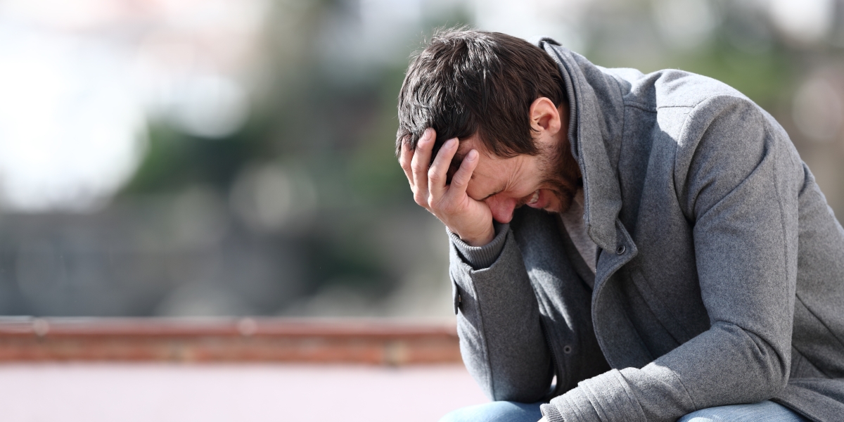 Man sitting on park bench looking regretful